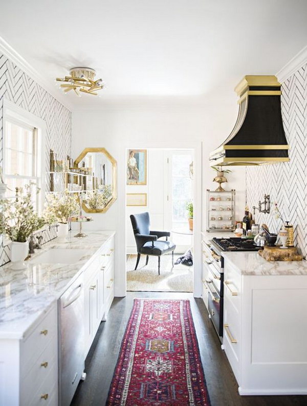 Mini White kitchen with Marble Countertops and black and gold hood over stove. 